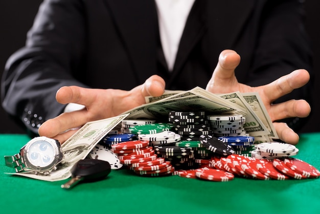 concepto de casino, juegos de azar, personas y entretenimiento: cierre del jugador de póquer con fichas, dinero y cosas personales en la mesa de casino verde