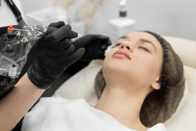 Concepto de cejas microblading. La cosmetóloga realiza el procedimiento de maquillaje permanente de las cejas en primer plano.