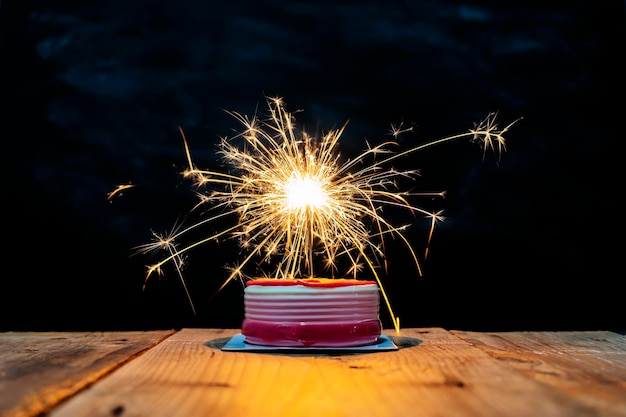 Concepto de celebración de éxito El pastel en la mesa tiene fuegos artificiales que iluminan la luz y se ven increíbles