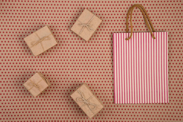 Concepto de celebración de papel artesanal con bolsas de regalo de bolsas de compras a rayas sobre fondo de papel artesanal en lunares rojos