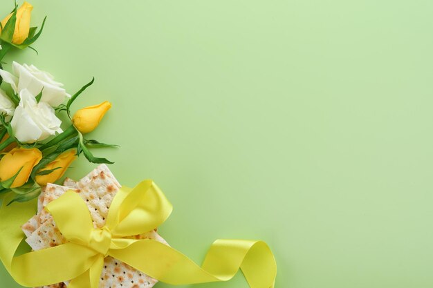 Concepto de celebración de Pascua Matzá kosher vino tinto nuez y flores de rosas blancas y amarillas de primavera Ritual tradicional pan judío sobre fondo verde claro Comida de Pascua Fiesta judía de Pesaj