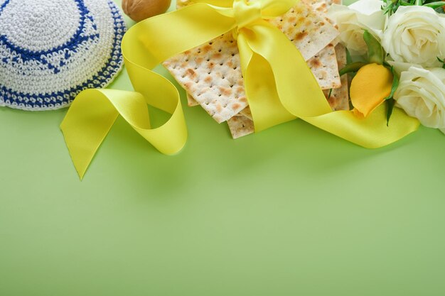 Concepto de celebración de Pascua Matzá kosher vino tinto nuez y flores de rosas blancas y amarillas de primavera Ritual tradicional pan judío sobre fondo verde claro Comida de Pascua Fiesta judía de Pesaj