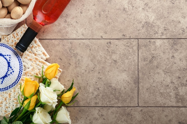 Concepto de celebración de Pascua Matzá kosher vino tinto nuez y rosas blancas y amarillas Ritual tradicional pan judío sobre fondo de pared de azulejo antiguo de color arena Comida de Pascua Fiesta judía de Pesaj