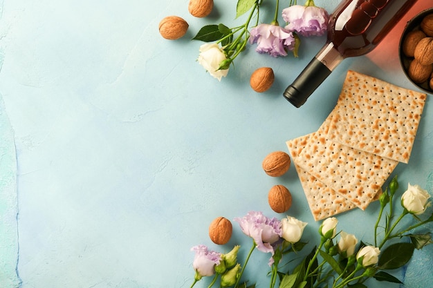 Concepto de celebración de Pascua Matzá rojo kosher nuez y primavera hermosas flores color de rosa Ritual tradicional Judío pan sobre fondo turquesa claro o azul Comida de Pascua Pesaj Fiesta judía