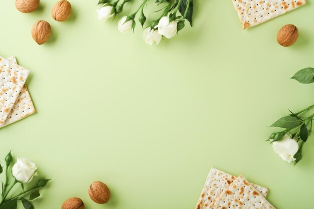 Concepto de celebración de Pascua Matzá rojo vino kosher nuez y primavera hermosas flores color de rosa Ritual tradicional pan judío sobre fondo verde claro Comida de Pascua Pesaj Fiesta judía