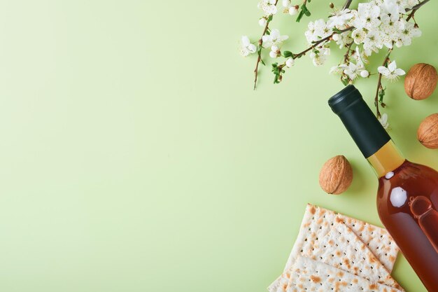 Concepto de celebración de Pascua Matzá vino rojo kosher nuez y primavera hermosa rama de cereza o manzana en plena floración Pan judío tradicional sobre fondo verde claro Festividad judía de Pesaj