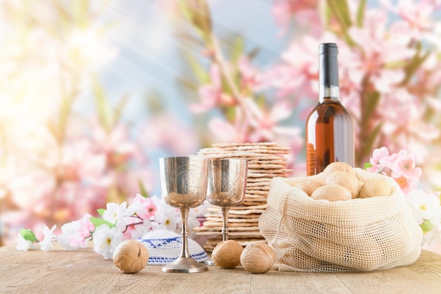 Concepto de celebración de la Pascua Matzah rojo kosher y nuez en mesa de madera vintage mesa frente a la primavera flor de árbol jardín y flores paisaje con rayos de sol con espacio de copia Mock up