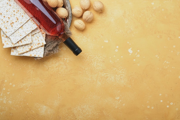 Concepto de celebración de Pesaj de Pascua Matzá kosher vino tinto nuez y rosas blancas y amarillas Ritual tradicional Pan judío sobre fondo de pared de azulejo antiguo de color arena Fiesta judía de Pesaj Vista superior