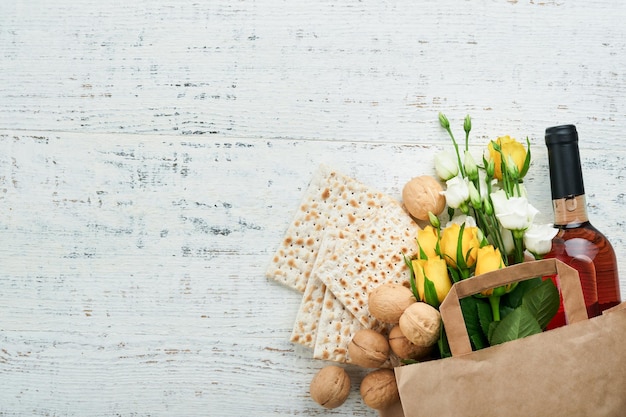 Concepto de celebración de Pesaj de Pascua Matzá kosher vino tinto nuez y rosas blancas y amarillas Ritual tradicional Pan judío sobre fondo de pared de azulejo antiguo de color arena Fiesta judía de Pesaj Vista superior