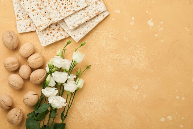 Concepto de celebración de Pesaj de Pascua Matzá kosher vino tinto nuez y rosas blancas y amarillas Ritual tradicional Pan judío sobre fondo de pared de azulejo antiguo de color arena Fiesta judía de Pesaj Vista superior