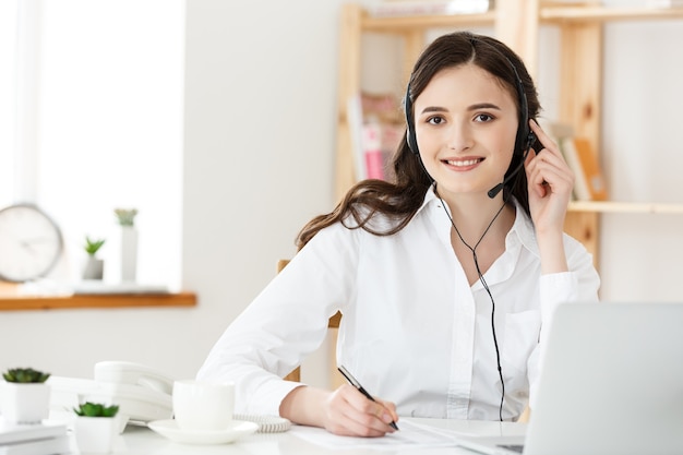 Concepto de centro de llamadas: Retrato de operador de telefonía de atención al cliente sonriente feliz en el lugar de trabajo.