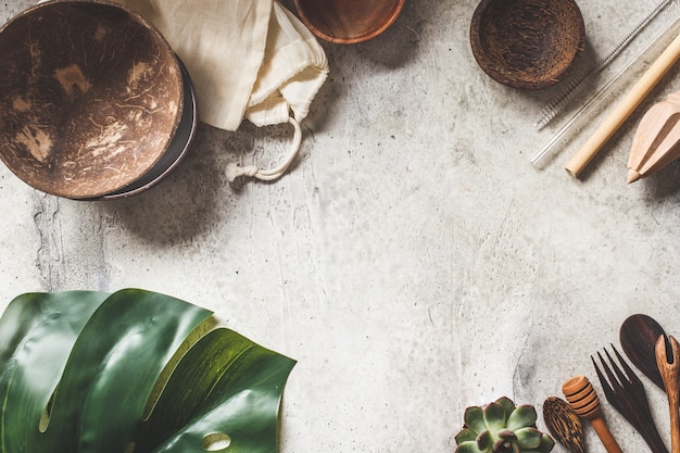 Concepto de cero residuos. Tazones de coco, cubiertos de madera, bolsas de algodón sobre fondo gris, espacio de copia, vista superior.