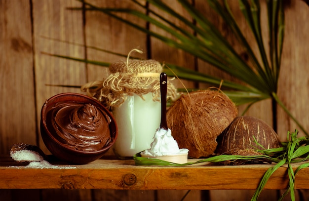 Concepto de chocolate y coco de spa en una mesa de madera. Tratamiento de chocolate para la piel corporal. Cuenco de chocolate derretido y aceite de coco