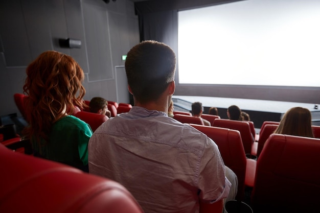 concepto de cine, entretenimiento, ocio y personas - pareja viendo películas en el teatro desde atrás