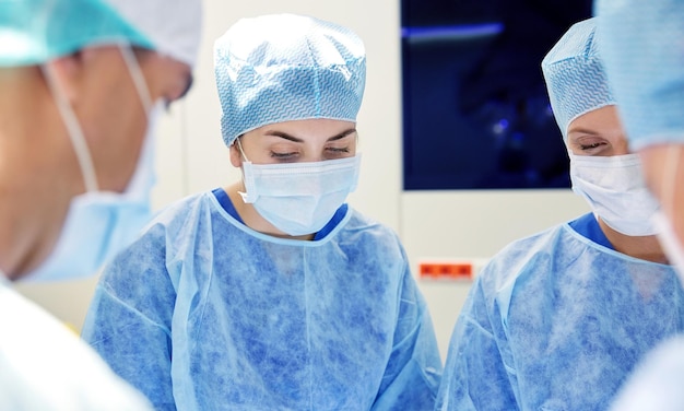 concepto de cirugía, medicina y personas - grupo de cirujanos en operación en sala de operaciones en el hospital