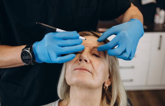 Concepto de cirugía plástica Manos marcando rostro masculino sobre fondo gris