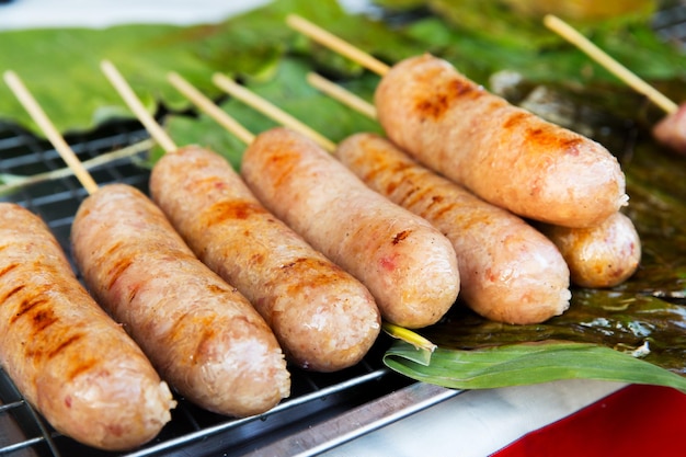 concepto de cocina, cocina asiática, venta y comida - salchichas a la parrilla en el mercado callejero