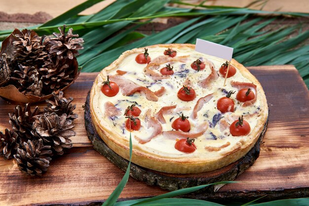 Concepto de cocina francesa e italiana. Pastel con verduras y tocino. tomates cherry, cebollas, tocino y especias en una mesa de madera