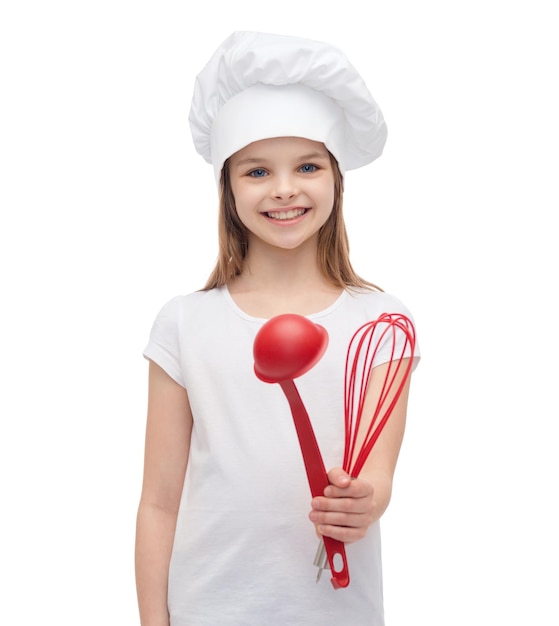 concepto de cocina y gente - niña sonriente con sombrero de cocinero con cucharón y batidor