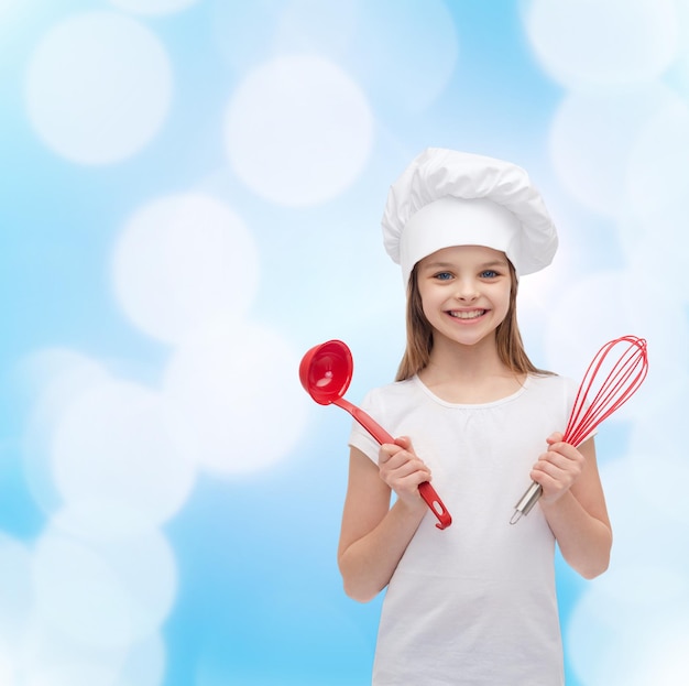 concepto de cocina y gente - niña sonriente con sombrero de cocinero con cucharón y batidor