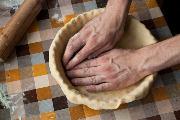 Concepto de cocina y hogar - cerca de manos masculinas amasar