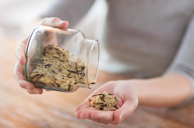 Concepto de cocina y hogar: cierre del frasco de vaciado femenino con una mezcla de arroz blanco y negro salvaje