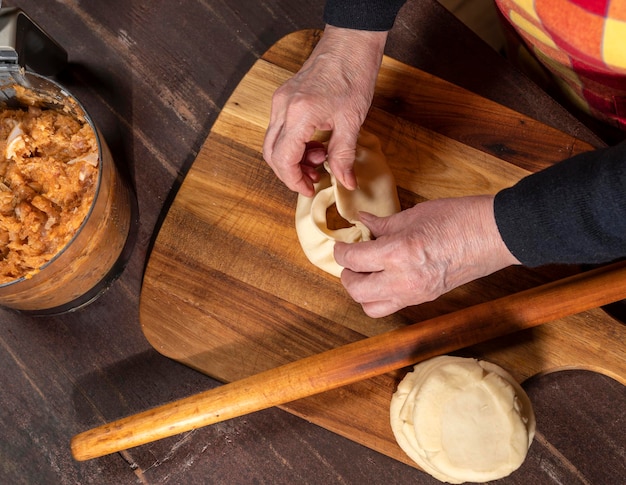 Concepto de cocina y hogar. Mujer preparando tartas caseras con relleno de carne picada en la mesa de la cocina en casa