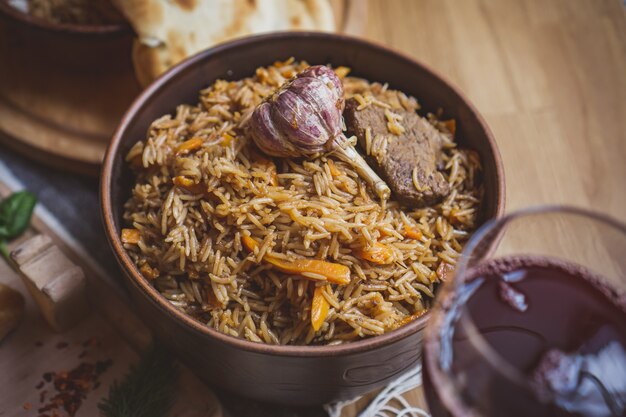 El concepto de cocina oriental. Pilaf uzbeko georgiano casero o plov de cordero servido en utensilios de cocina de hierro fundido.