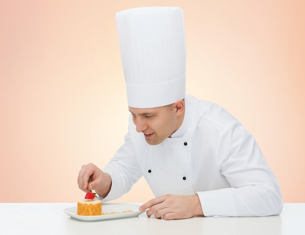 concepto de cocina, profesión, alta cocina, comida y personas - feliz chef masculino decorando el postre sobre fondo beige