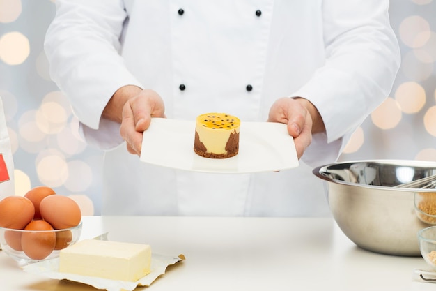 concepto de cocina, profesión, alta cocina, comida y personas - primer plano de un chef masculino que cocina el postre durante las vacaciones luces de fondo