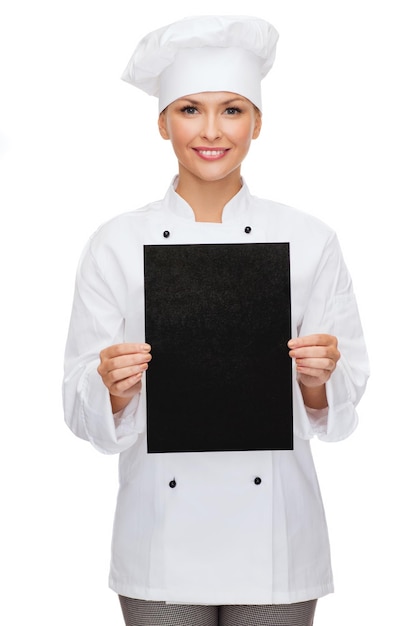 concepto de cocina, publicidad y comida - chef sonriente, cocinera o panadera con papel negro en blanco