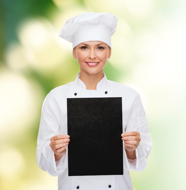 concepto de cocina, publicidad y comida - chef sonriente, cocinera o panadera con papel negro en blanco