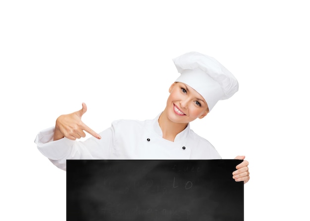 concepto de cocina, publicidad y personas - chef sonriente, cocinera o panadera señalando con el dedo a la pizarra en blanco sobre fondo blanco