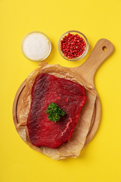 Concepto de cocinar con bistec crudo sobre fondo amarillo