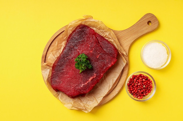 Concepto de cocinar con bistec de ternera cruda sobre fondo amarillo