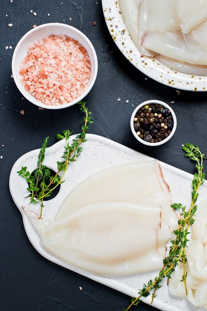El concepto de cocinar calamares crudos Ingredientes para cocinar tomillo, pimienta, sal rosada.
