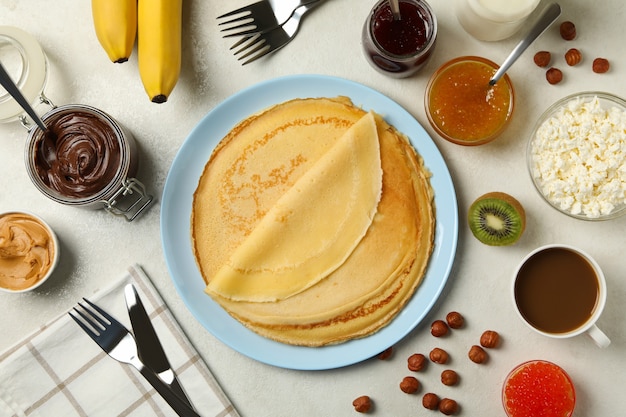 Concepto de cocinar el desayuno con panqueques finos e ingredientes sobre fondo blanco con textura