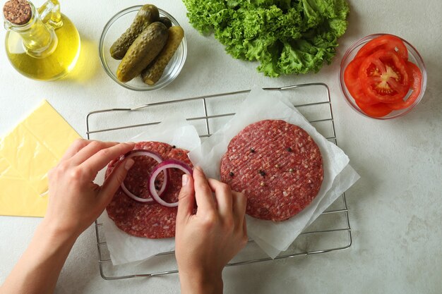 Concepto de cocinar hamburguesas en la mesa con textura blanca