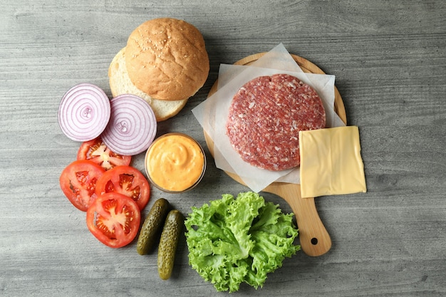 Concepto de cocinar hamburguesas en mesa con textura gris