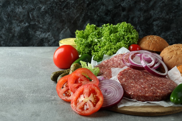 Concepto de cocinar hamburguesas en mesa con textura gris