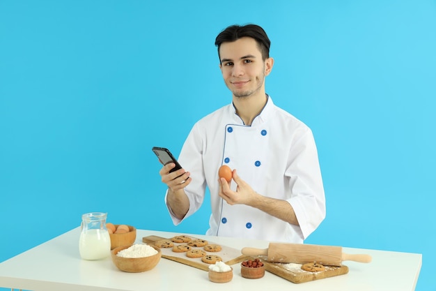 Concepto de cocinar joven chef sobre fondo azul.