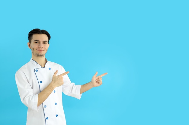 Concepto de cocinar joven chef sobre fondo azul.