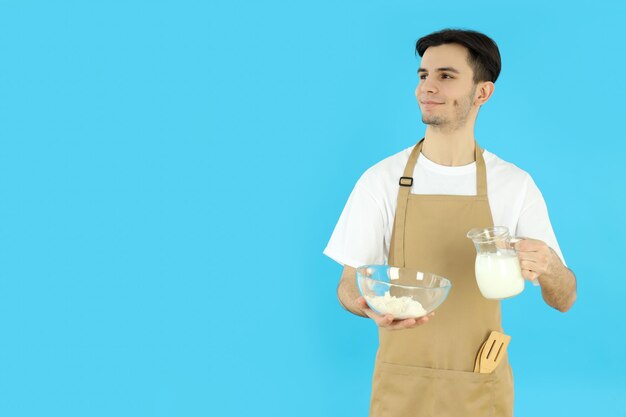 Concepto de cocinar joven en delantal sobre fondo azul.