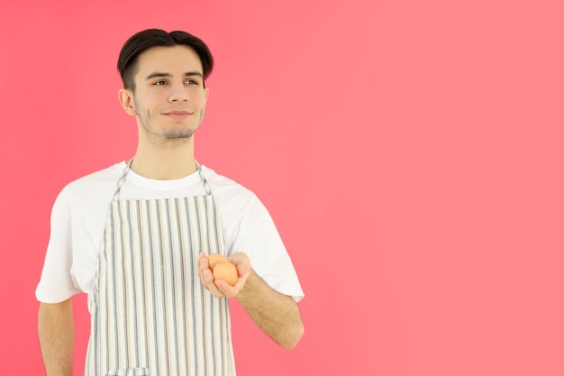 Concepto de cocinar joven en delantal sobre fondo rosa