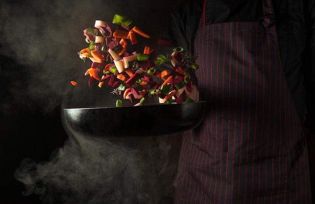 El concepto de cocinar verduras frescas de la mano de un chef profesional en la cocina