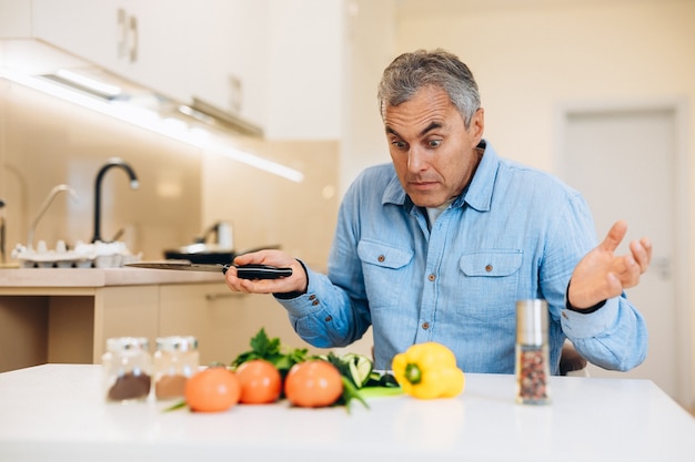 Concepto de cocinero aficionado. Hombre maduro sorprendido no sabe cocinar un plato