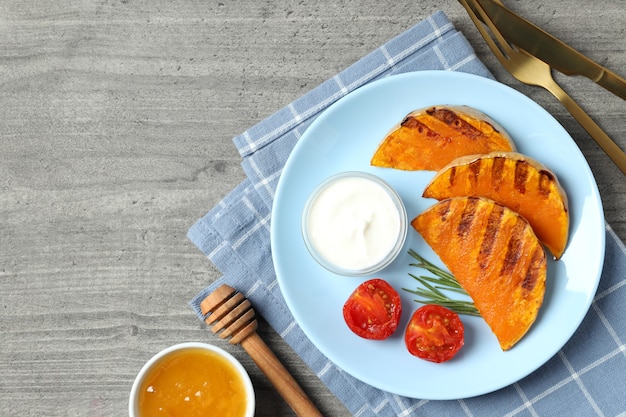 Concepto de comer sabroso con calabaza al horno sobre fondo de textura gris.