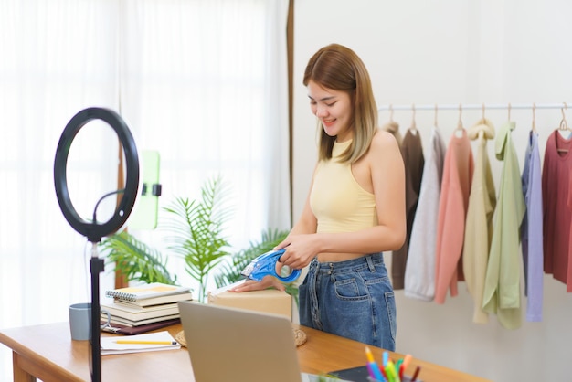 Concepto de comerciante en línea Diseñador de moda empacando ropa en una caja de paquetes y envolviéndola para la entrega