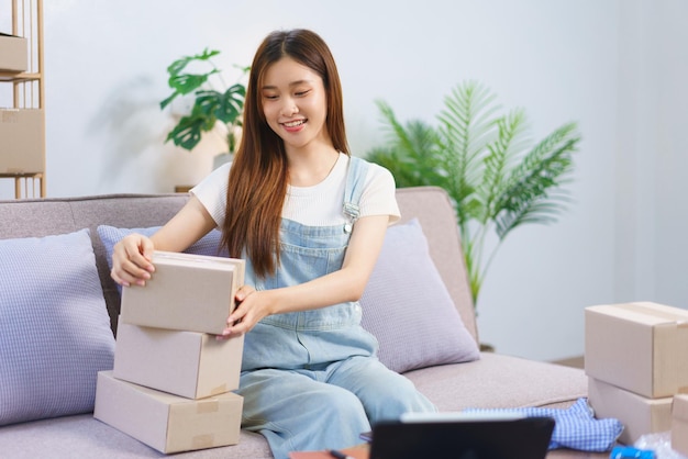 Concepto de comerciante en línea Mujer empresaria revisando cajas de paquetes mientras prepara el envío al cliente