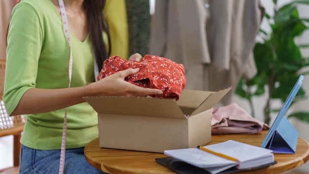 Concepto de comerciante de ropa de moda Blogger femenina empacando el producto en una caja para preparar el envío al cliente